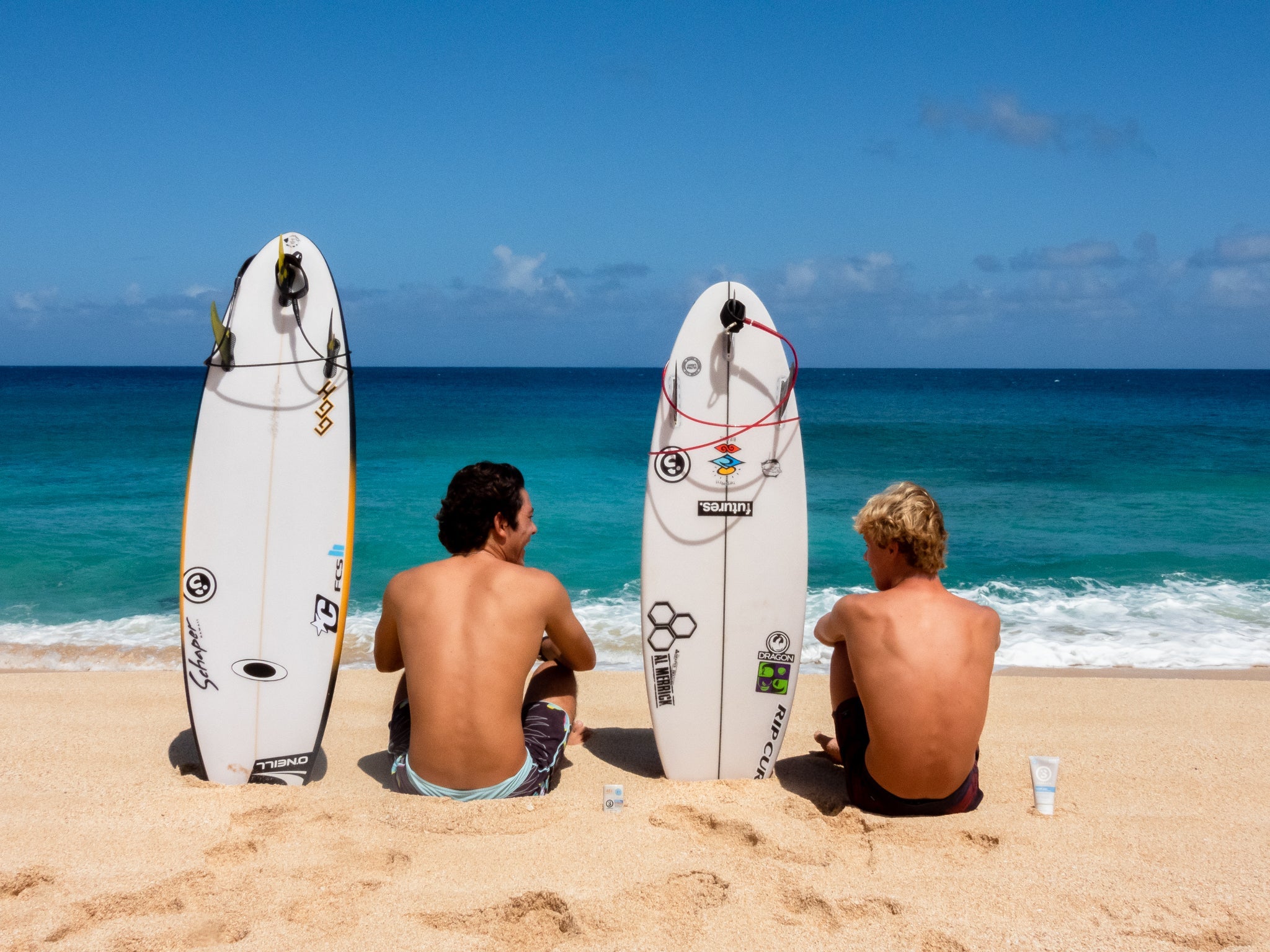 2 Boys Sitting on Hawaii Beach With Surfboards and Zinc Sunscreen