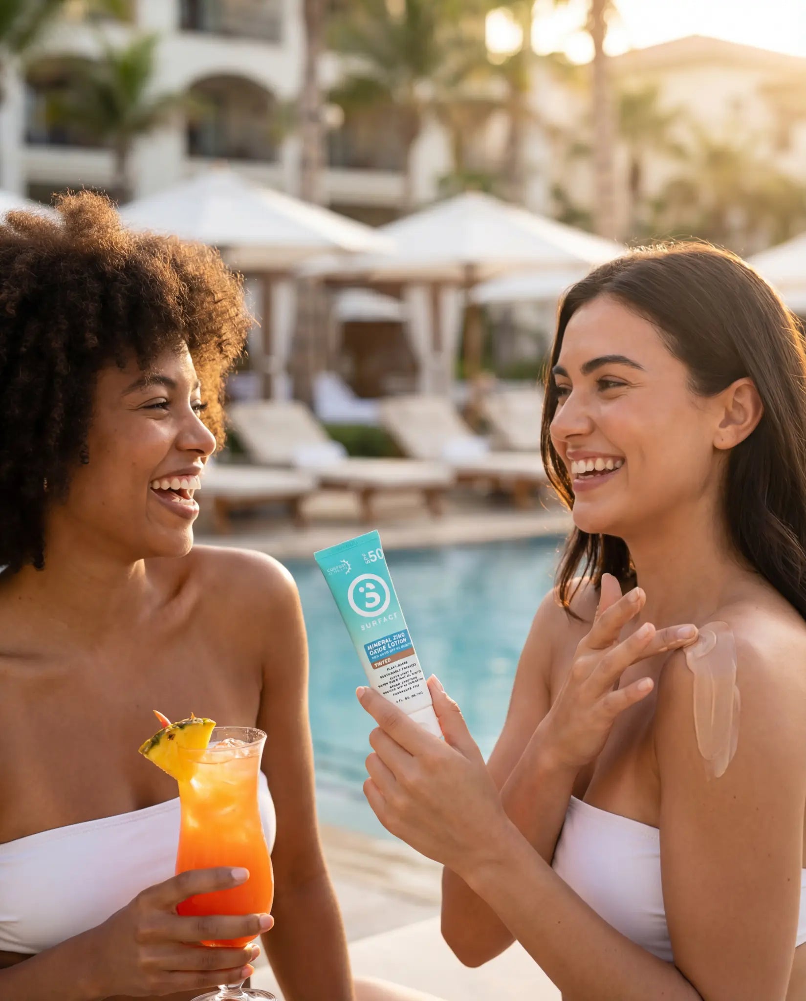 two women sitting poolside putting on sunscreen and smiling