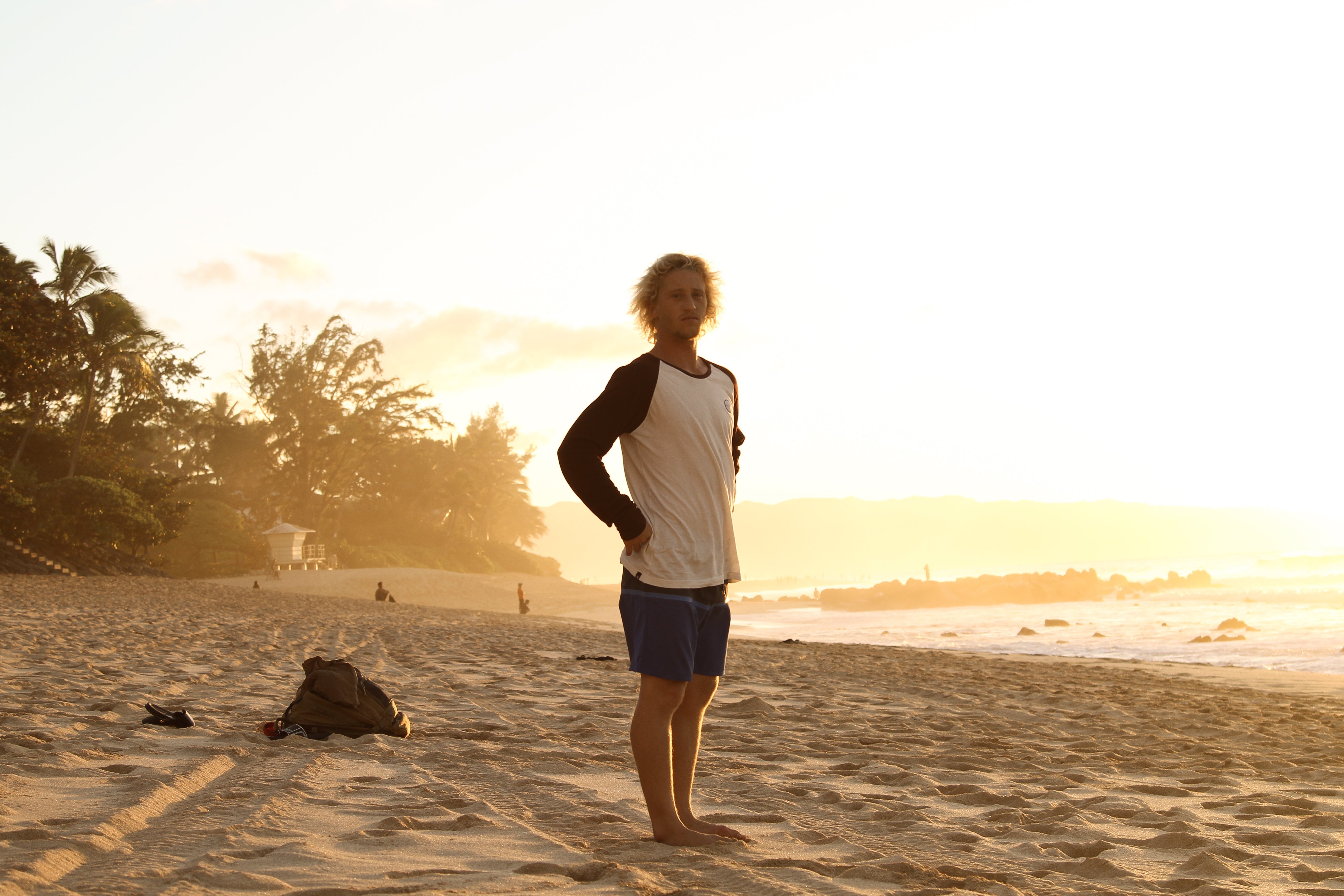 Man standing on tropical beach during sunset looking at the ocean